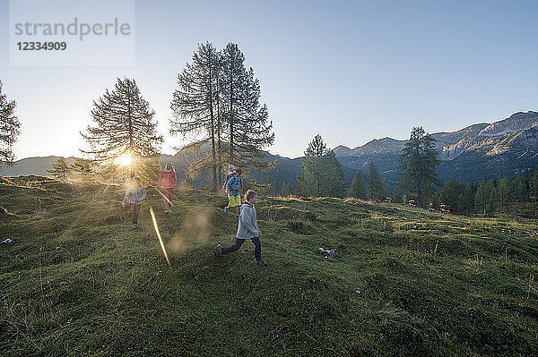 Family hiking in alpine meadow at sunset