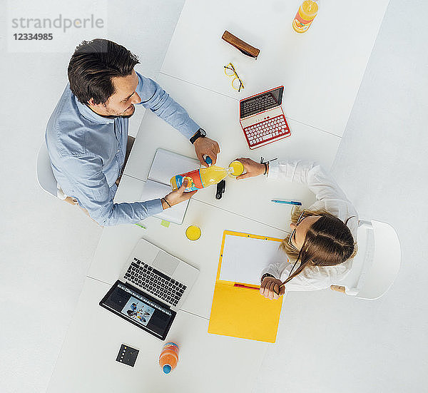 Two business people at meeting table in office  top view