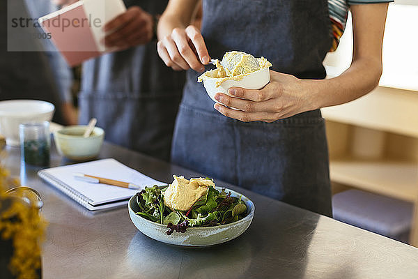 Close-up of woman preparing salad with icecream in kitchen
