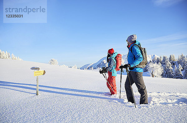 Austria  Tyrol  couple snowshoeing  standing in front of sign post