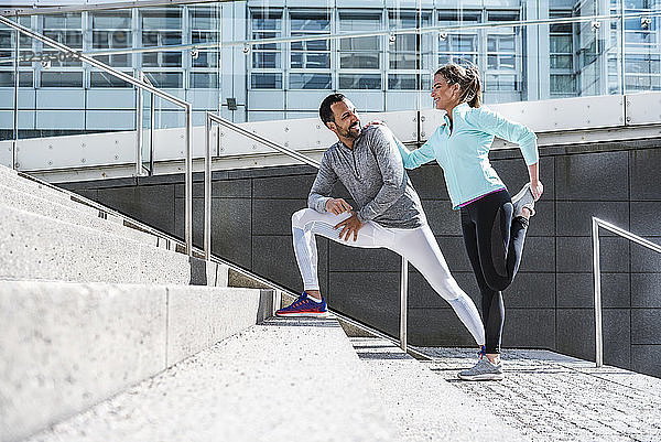 Couple doing stretching exercise on stairs in the city