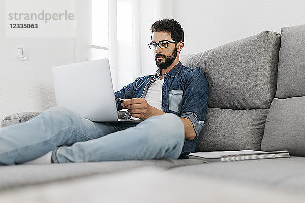 Man using laptop  working on the couch at home