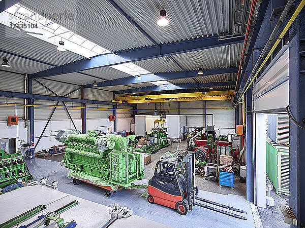Fork-lift driver pulling gas engine out of factory shop floor