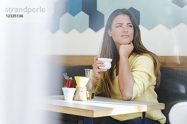 Young woman in a cafe holding cup of coffee