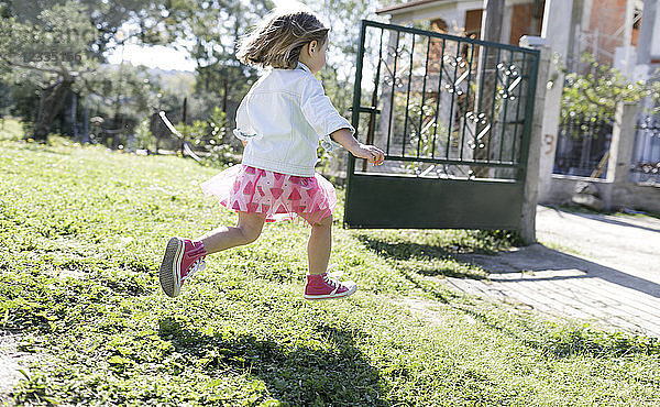 Little girl running on meadow in the garden