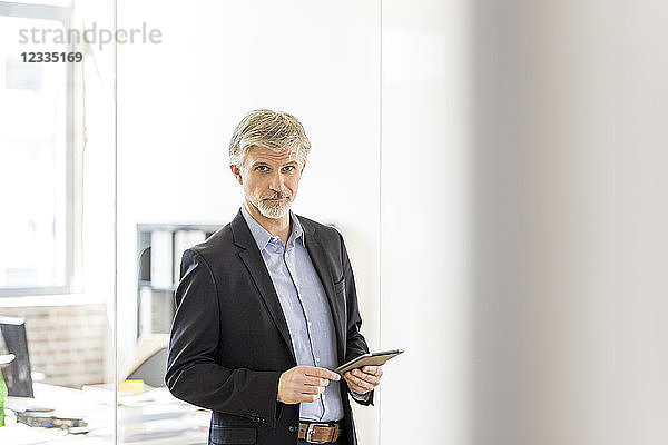 Mature man standing in his office  using didgital tablet