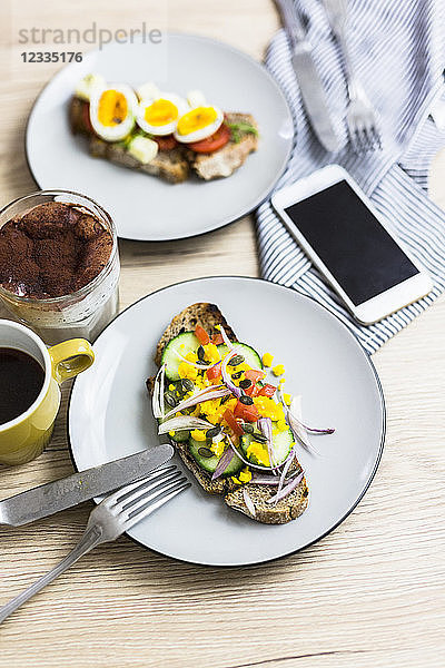 Vegetarian breakfast with bread  eggs and cucumber slices on plate  smartphone  latte macchiato  coffee cup