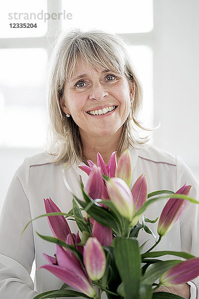 Portrait of smiling mature woman holding bunch of flowers