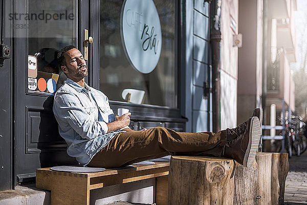 Relaxed man sitting outside a cafe enjoying the sunshine