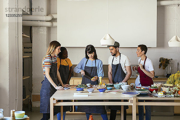 Friends and instructor in a cooking workshop preparing food