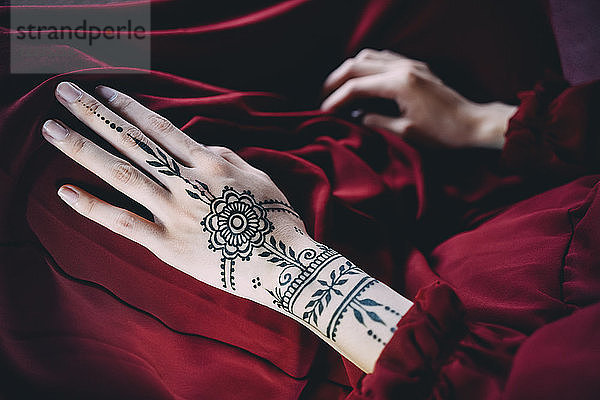 Woman's hand with henna tattoo on red cloth