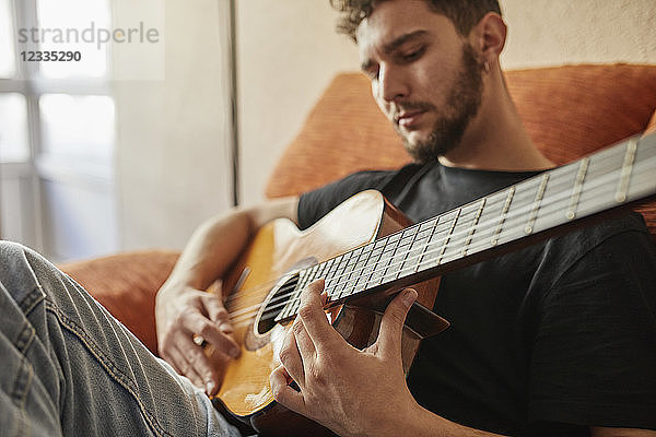 Man playing guitar on couch