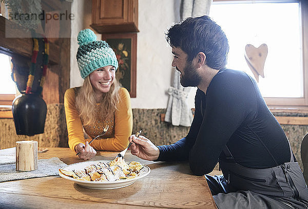 Happy couple eating in rustic mountain hut