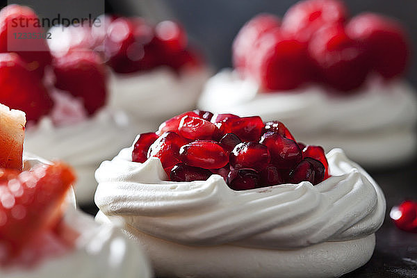Meringue pastry garnished with whipped cream and pomegranate seed