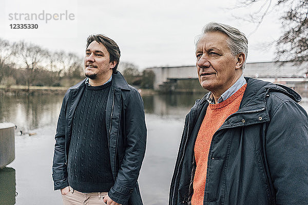 Senior man and young man standing at the riverside