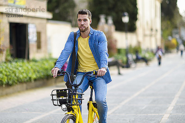 Young man riding rental bike in the city