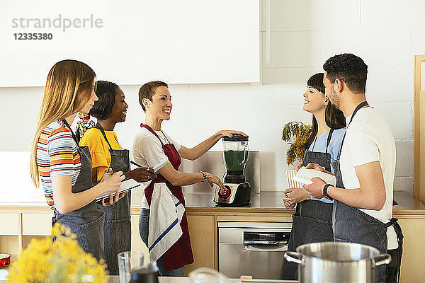 Friends and instructor in a cooking workshop preparing a smoothie