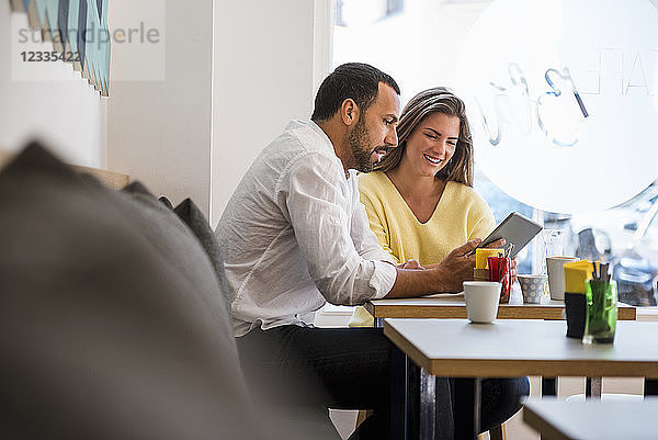 Young woman and man sharing tablet in a cafe