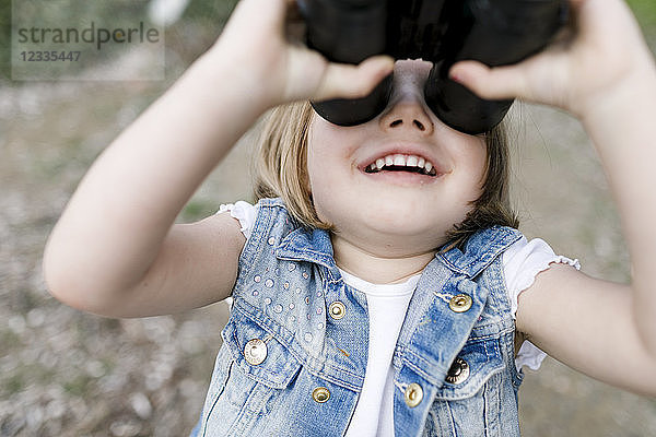 Happy little girl using binoculars