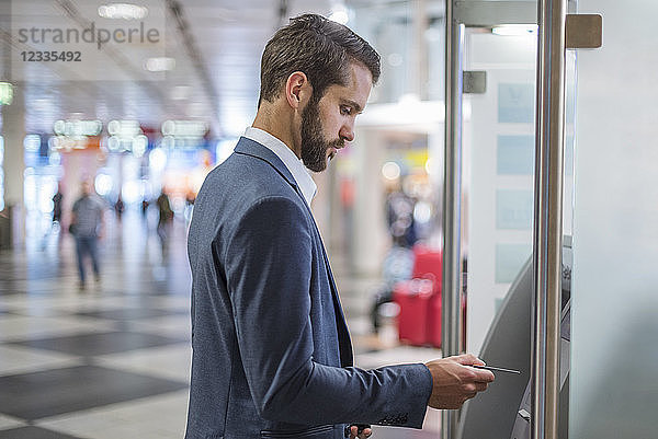 Young businessman withdrawing money at an ATM in the city