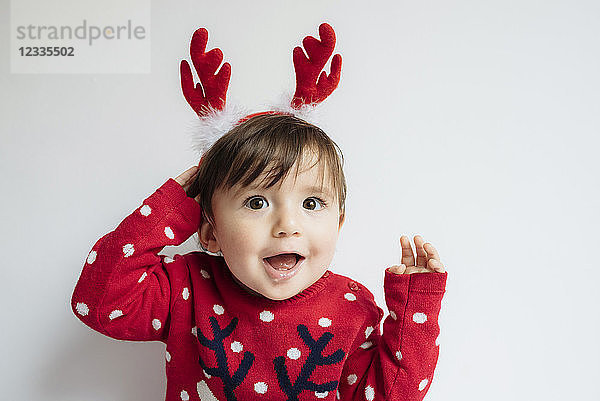 Portrait of baby girl with reindeer antlers headband at Christmas time