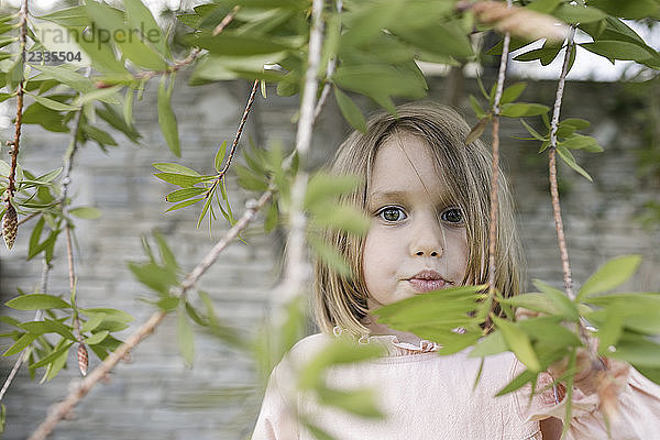 Portrait of little girl between twigs in a garden