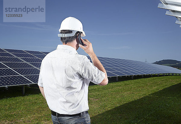 Back view of engineer on the phone in front of solar plant