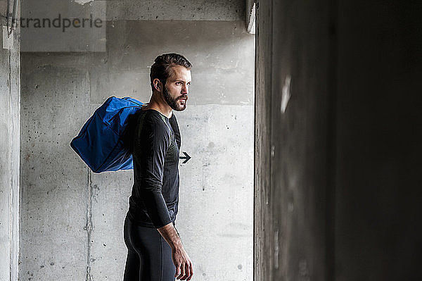 Athlete holding bag at concrete wall