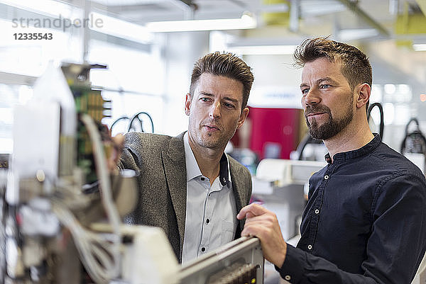 Two businessmen examining device in factory