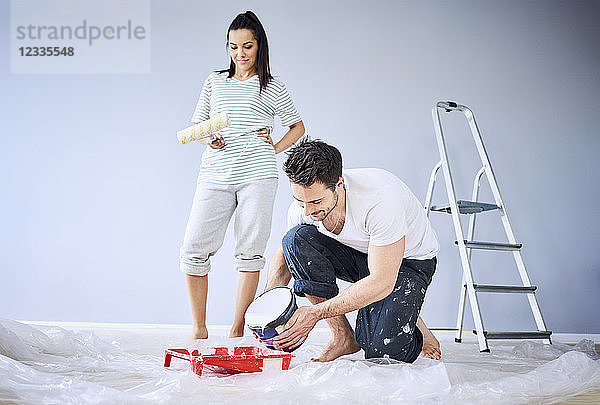 Happy couple painting in apartment together