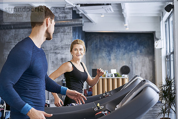 Man and woman talking during treadmill exercise at gym