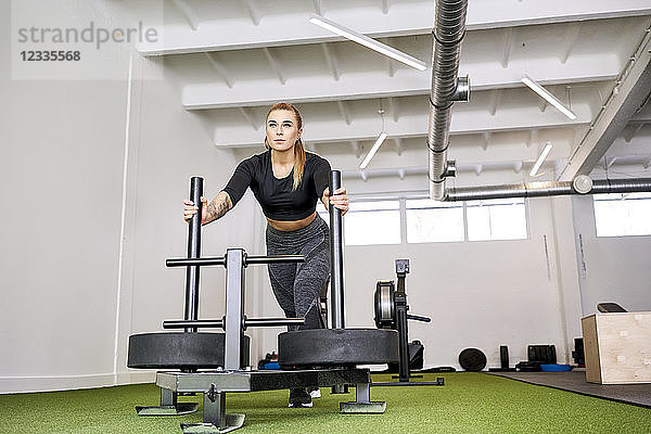 Woman pushing weight sled at gym