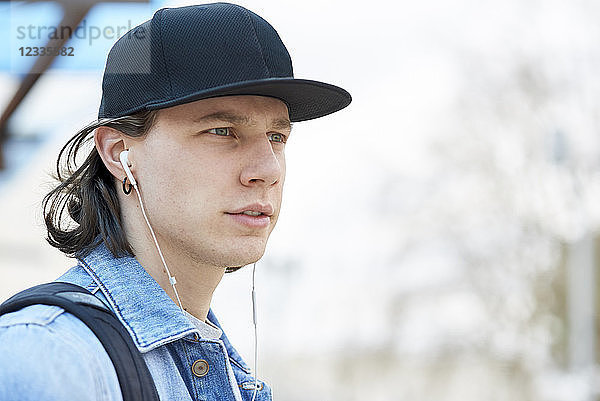 Portrait of a young man wearing baseball cap and ear buds