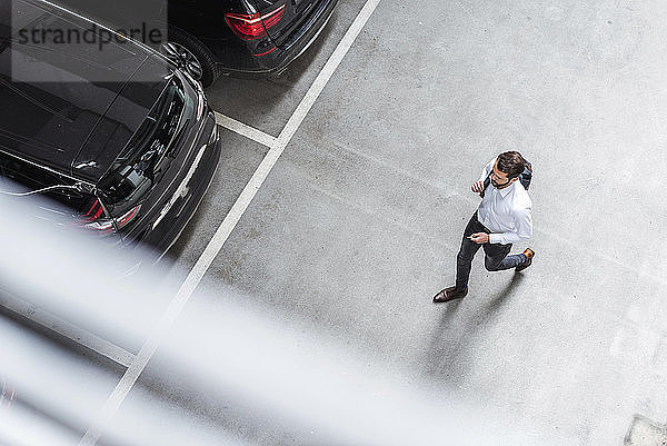 Young businessman with backpack on the go at parking garage