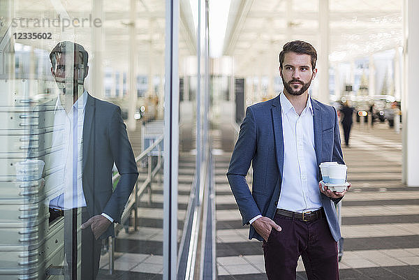 Young businessman holding tray with takeaway coffee