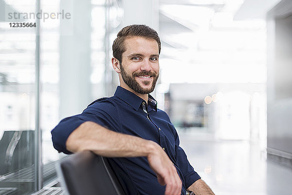 Portrait of smiling young businessman sitting in waiting area