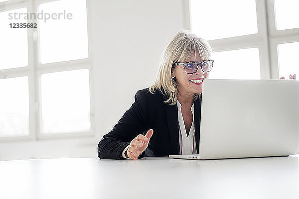Smiling mature businesswoman working on laptop at desk in the office