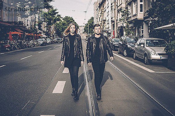 Young couple wearing black matching clothes walking side by side on the street