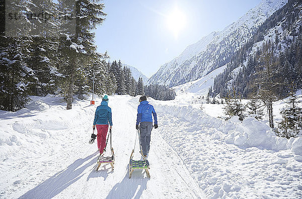 Couple with sledge walking in snow-covered landscape
