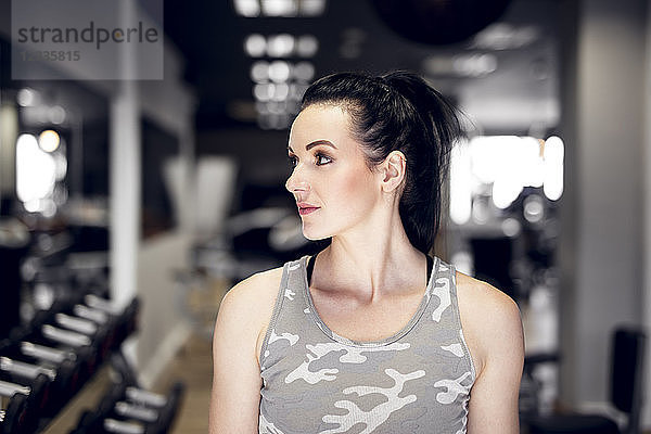 Sportive woman in gym looking sideways