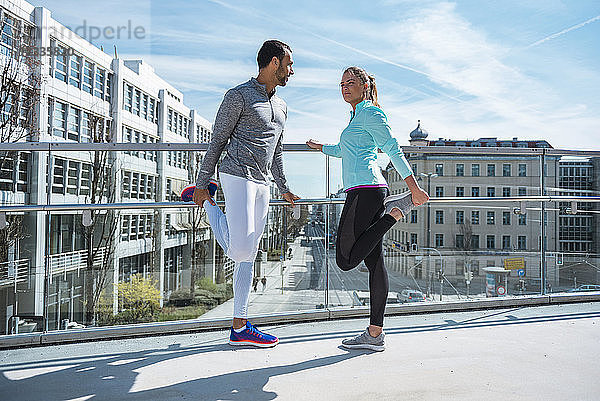Couple doing stretching exercise on bridge in the city