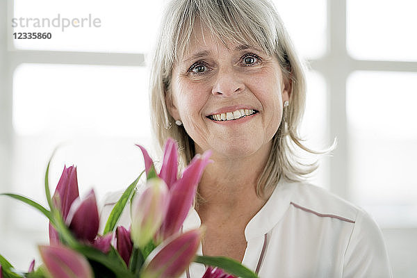 Portrait of smiling mature woman holding bunch of flowers