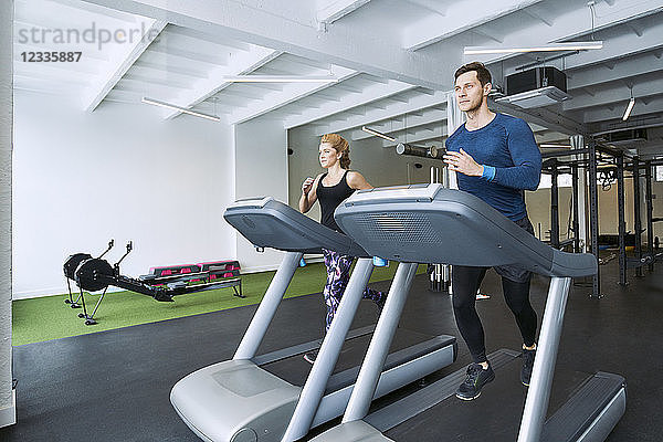 Man and woman running on treadmill at gym