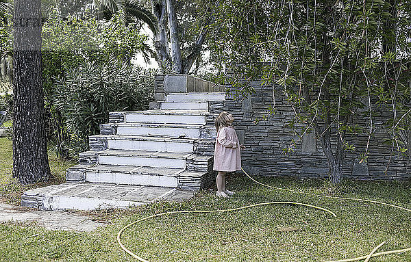 Little girl standing in garden looking up to tree