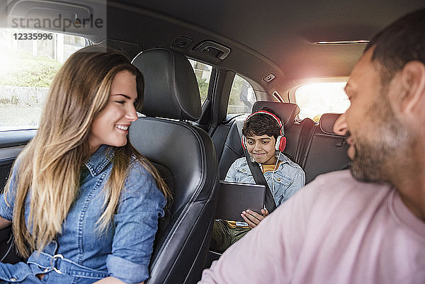 Family on a road trip with boy using tablet