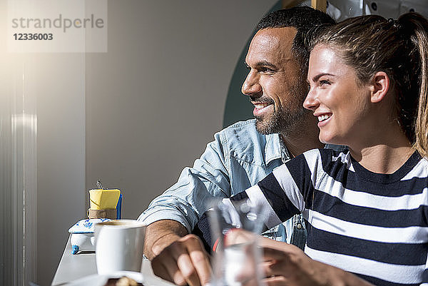 Happy couple in a cafe looking out of window