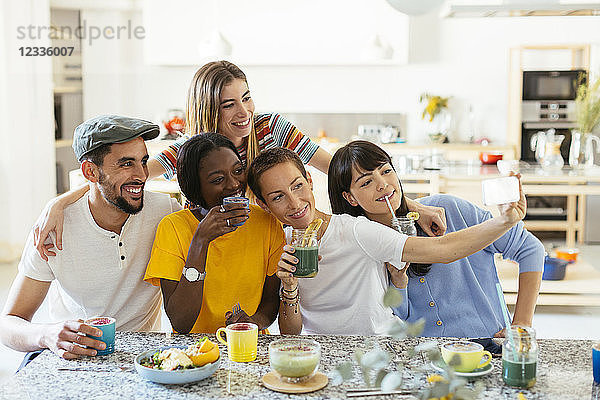 Friends with drinks taking a selfie in kitchen