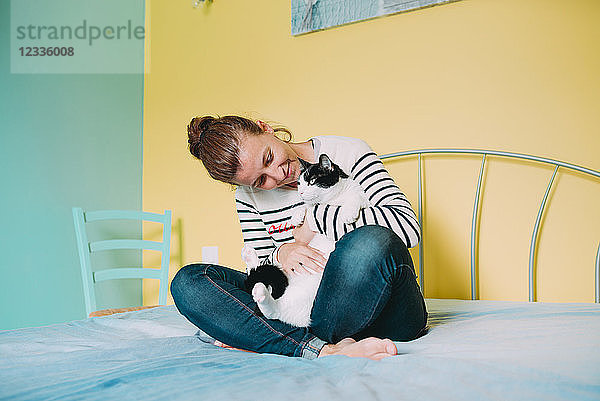 Happy woman with a black and white cat on the bed