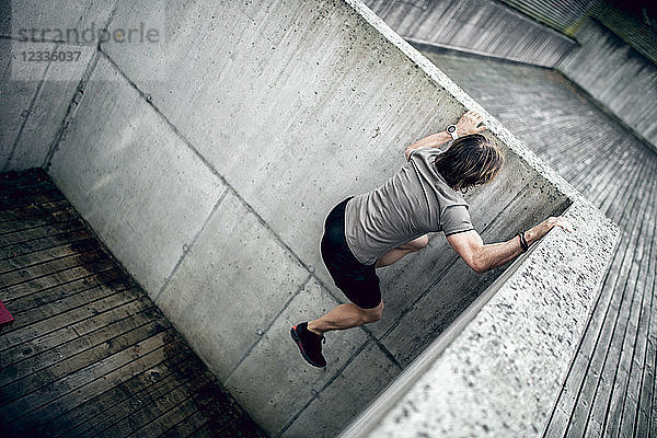 Athlete climbing up concrete wall outdoors