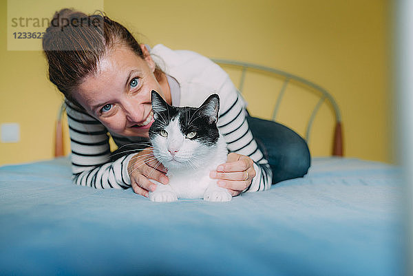 Happy woman with a black and white cat on the bed